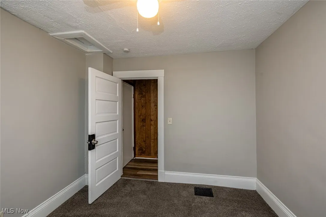 Spare room featuring a textured ceiling and dark colored carpet
