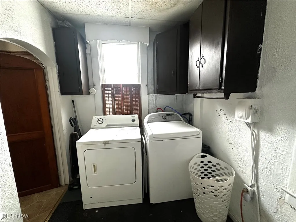 Clothes washing area featuring cabinets, electric panel, and independent washer and dryer