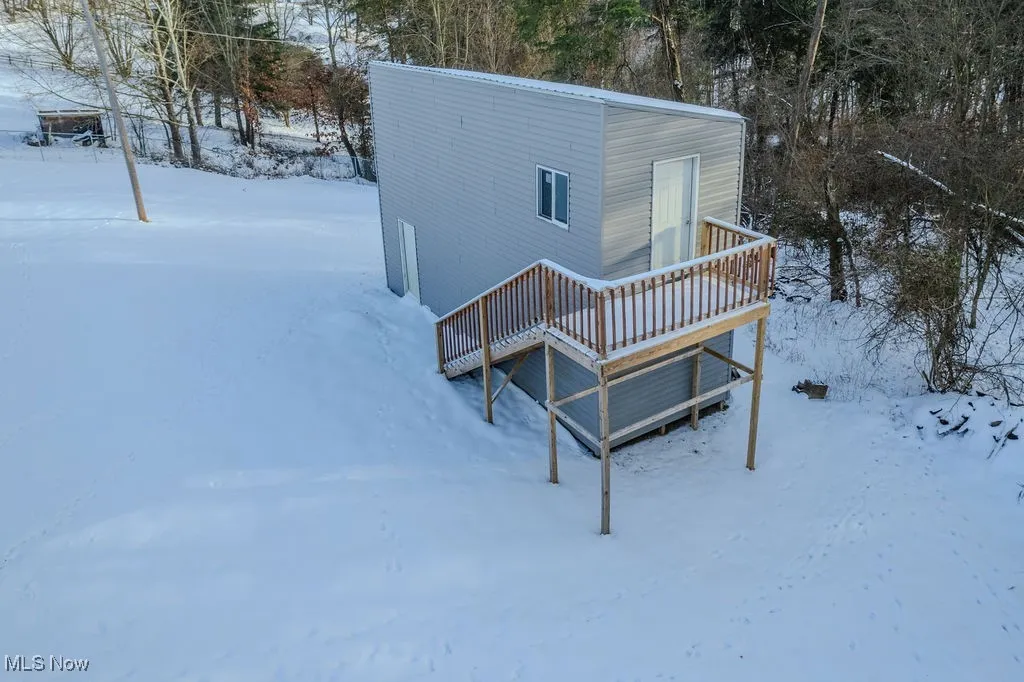 Snow covered back of property featuring a deck