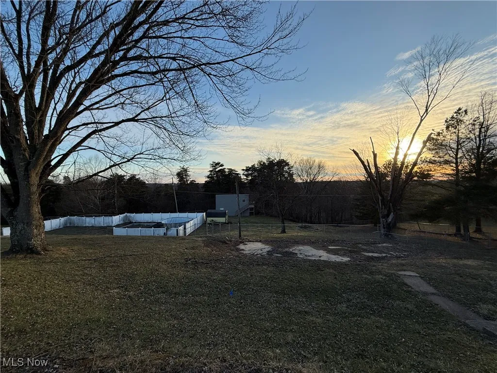 Yard at dusk with fence and a fenced in pool