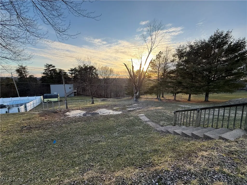 Yard at dusk with fence and a fenced in pool