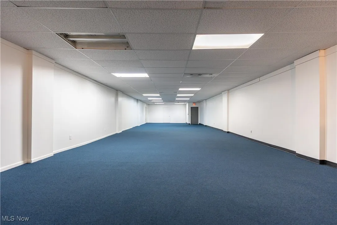 Empty room with a paneled ceiling and dark carpet