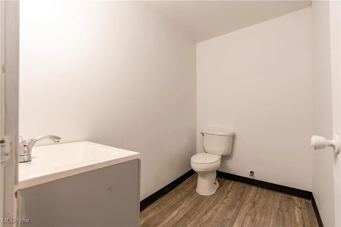 Bathroom with wood-type flooring, toilet, vaulted ceiling, and vanity
