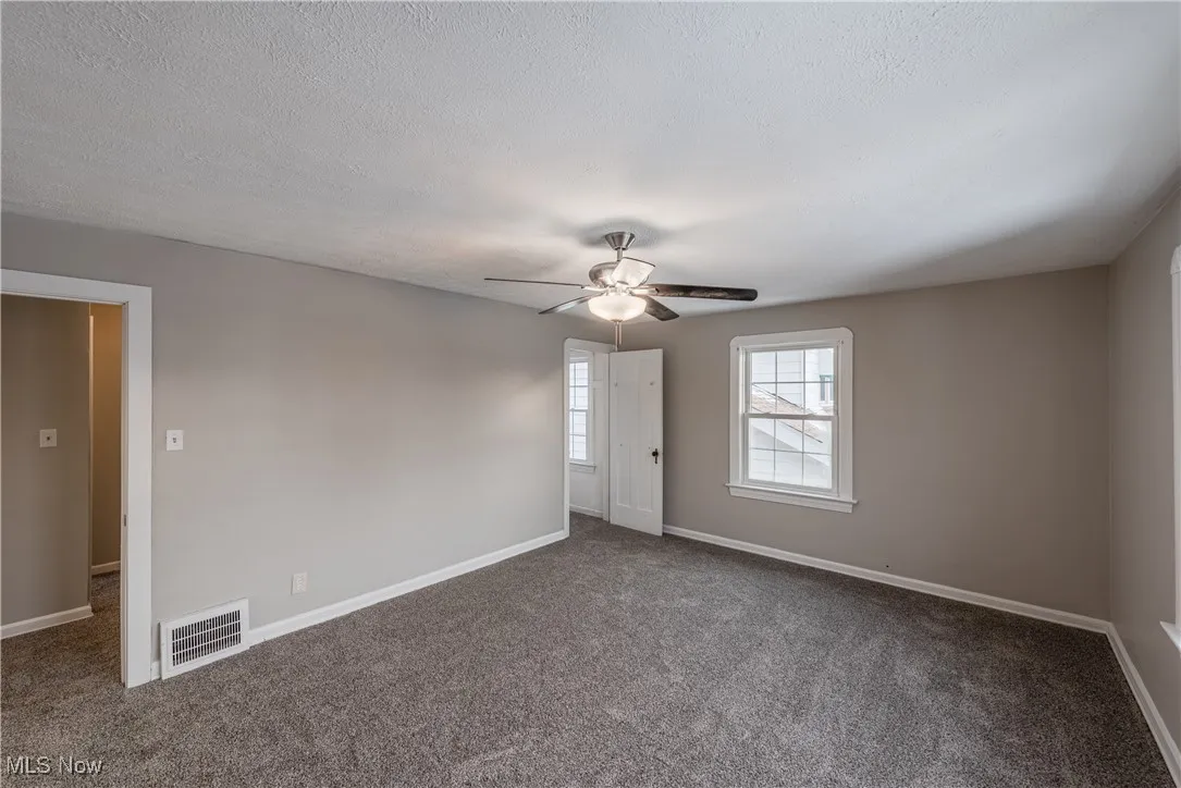 Carpeted spare room featuring ceiling fan
