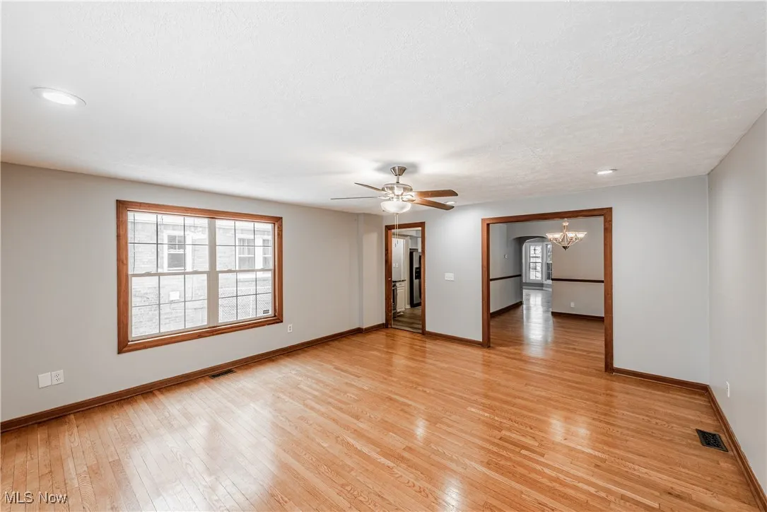 Family room featuring light wood-type flooring, ceiling fan with notable chandelier, and plenty of natural light