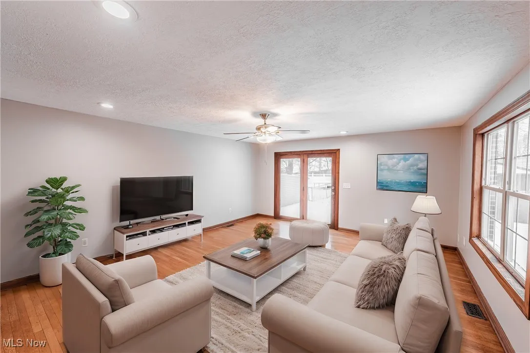 Living room featuring a healthy amount of sunlight, a textured ceiling, and light hardwood / wood-style floors (Virturally Staged)
