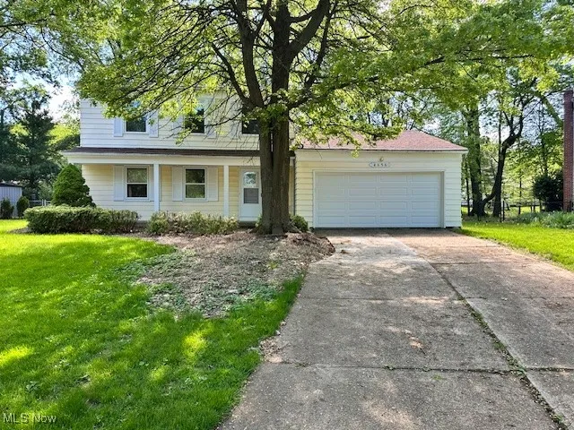 View of front facade featuring a front lawn, driveway, a garage, and a porch