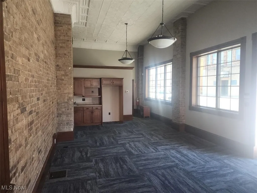 Kitchen featuring a high ceiling, brick wall, and decorative light fixtures