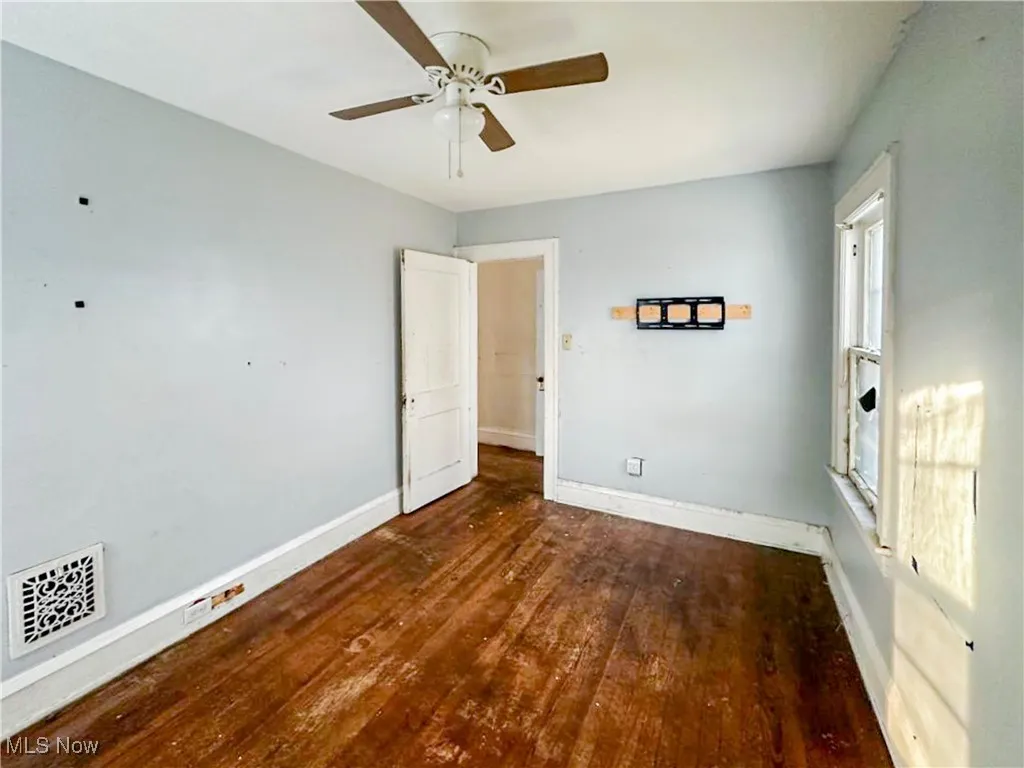 Empty room with ceiling fan and dark hardwood / wood-style floors