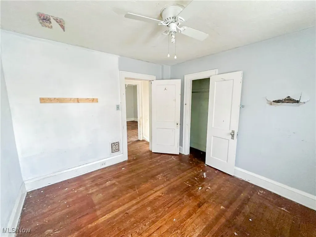 Unfurnished bedroom with dark wood-type flooring, ceiling fan, and a closet
