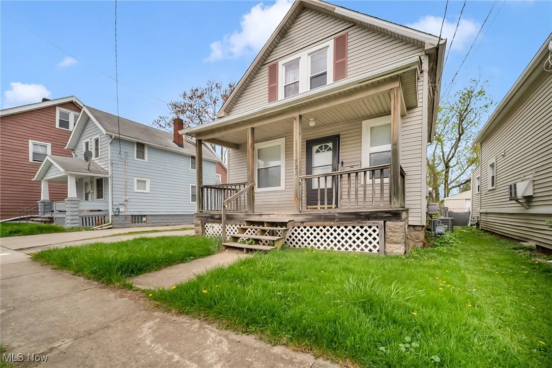 Bungalow-style house featuring a front lawn, a wall mounted AC, and covered porch