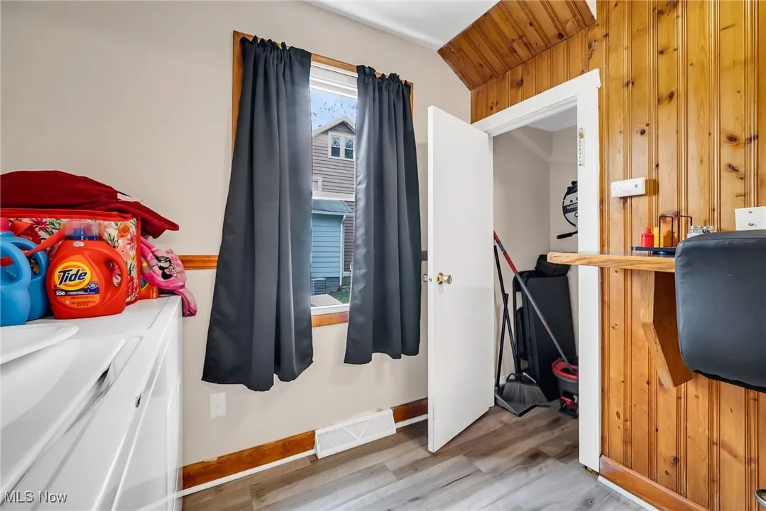 Bedroom with baseboards, visible vents, wood finished floors, and wooden walls