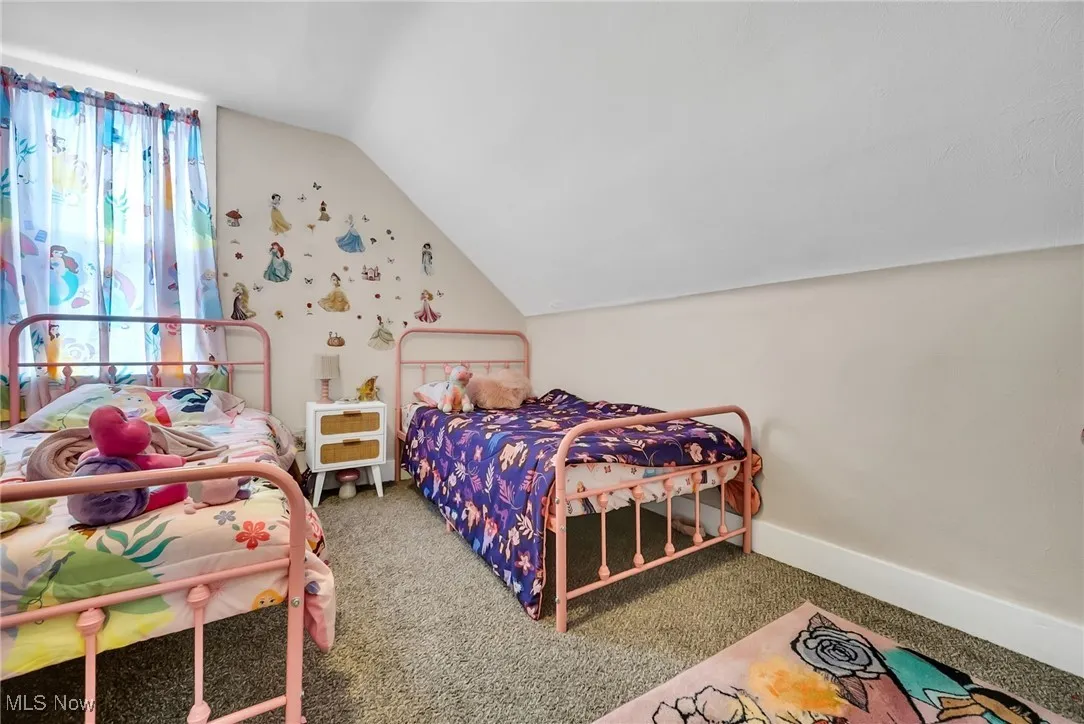 Carpeted bedroom featuring baseboards and lofted ceiling
