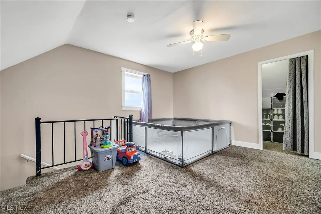 Unfurnished bedroom featuring carpet, ceiling fan, vaulted ceiling, and baseboards
