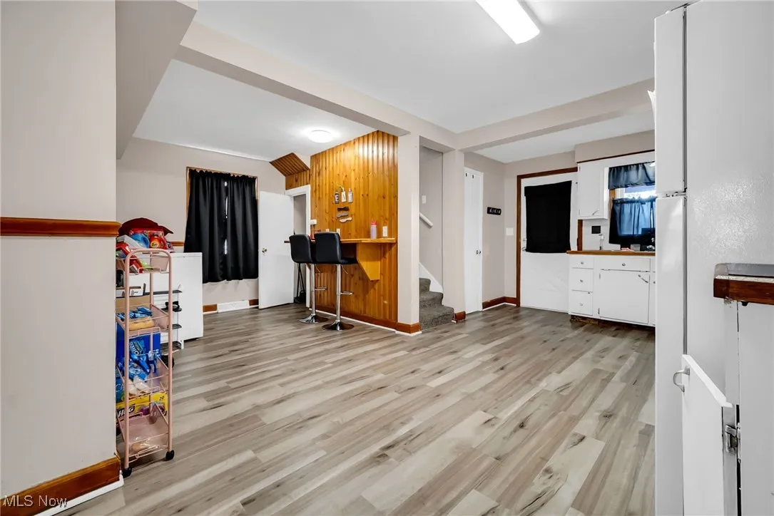 Living area with baseboards, stairway, indoor bar, and light wood finished floors