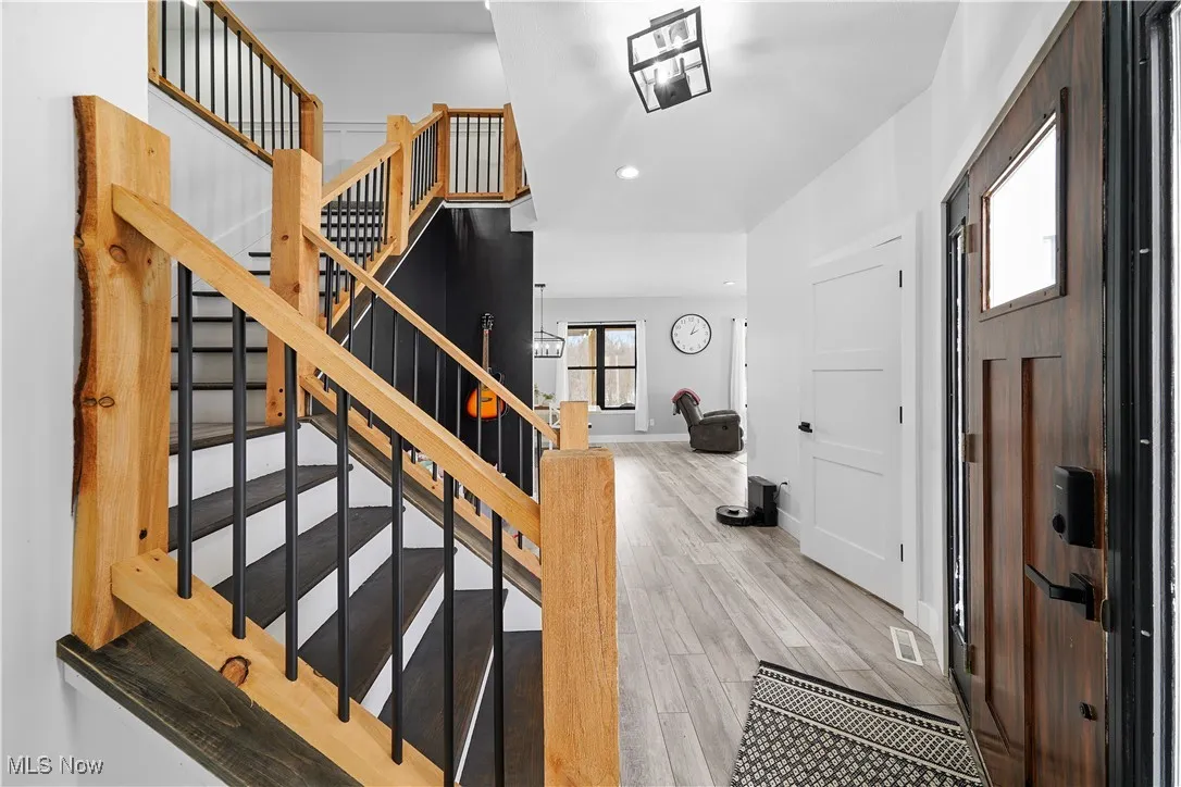 Staircase featuring wood-type flooring and a notable chandelier