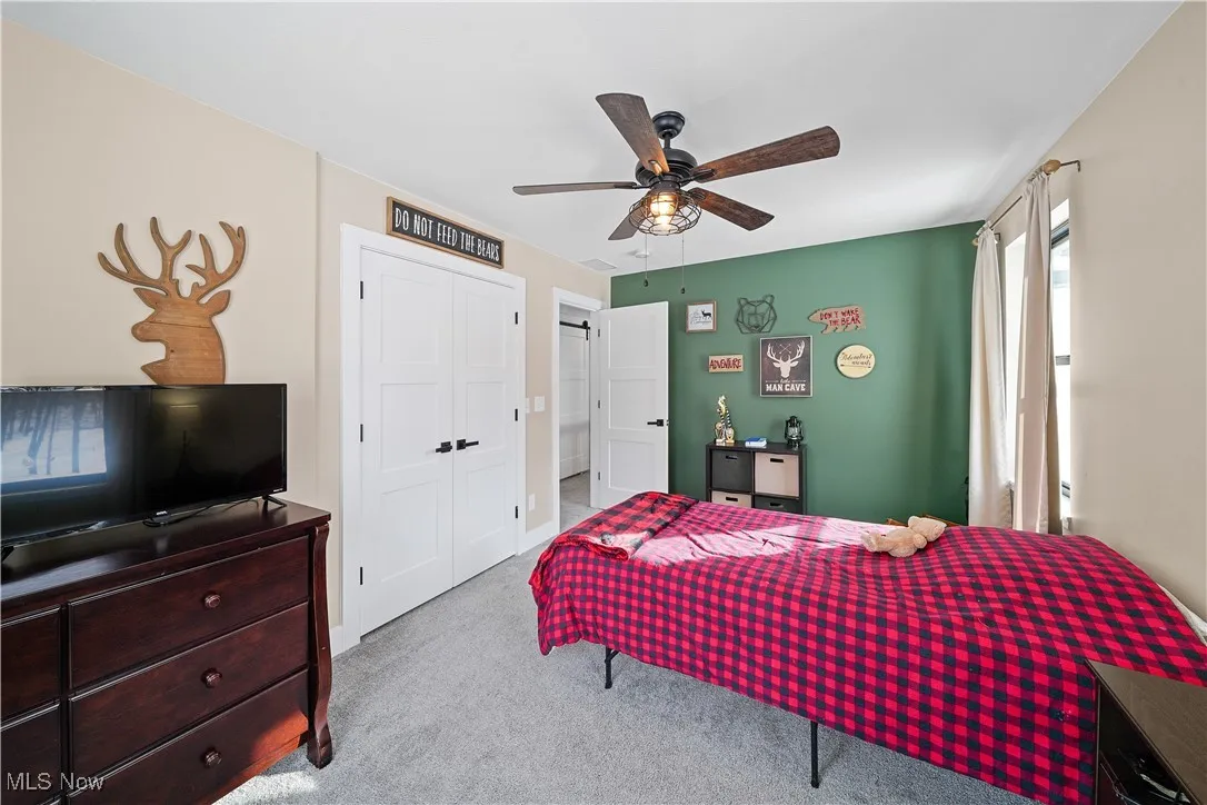 Bedroom with light colored carpet, a closet, and ceiling fan