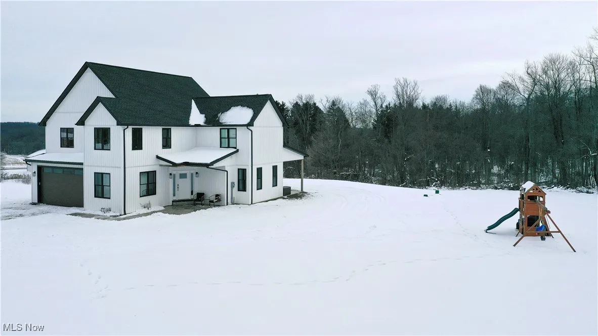 Snow covered property featuring a garage and a playground