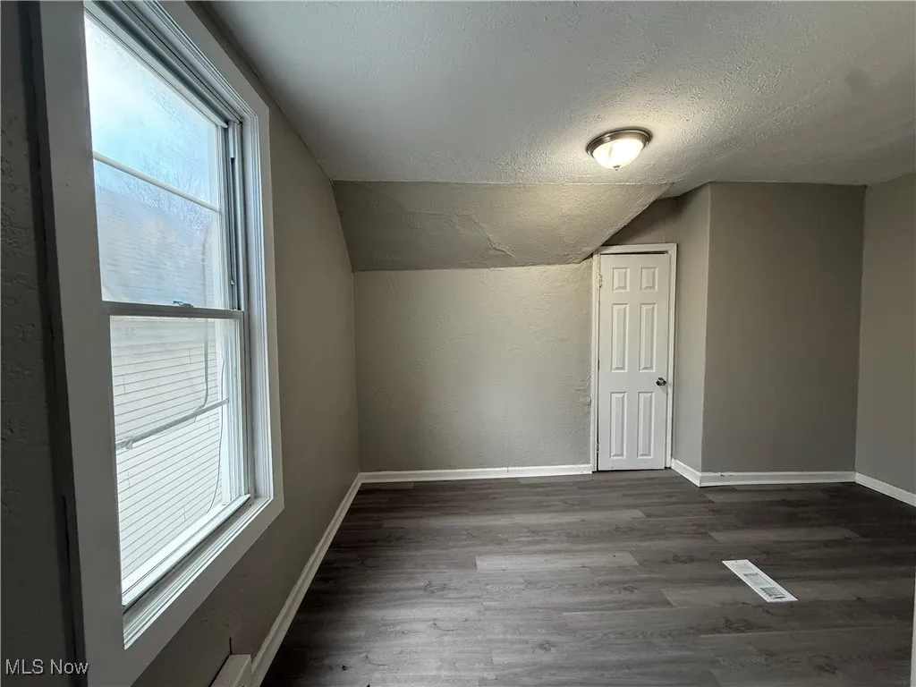 Bonus room with lofted ceiling, dark hardwood / wood-style floors, and a textured ceiling
