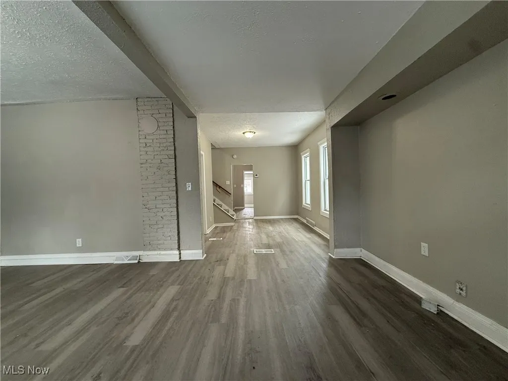 Unfurnished living room featuring dark wood-type flooring and a textured ceiling