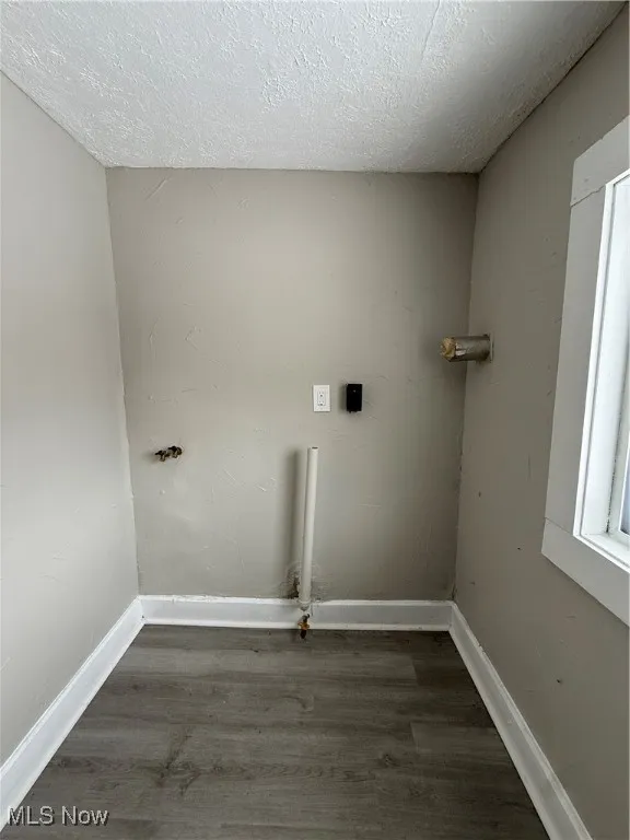 Laundry room featuring electric dryer hookup, dark hardwood / wood-style floors, and a textured ceiling