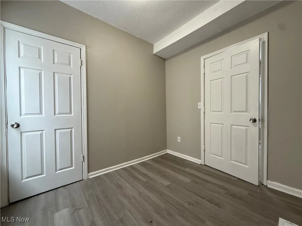 Unfurnished bedroom with dark wood-type flooring and a textured ceiling