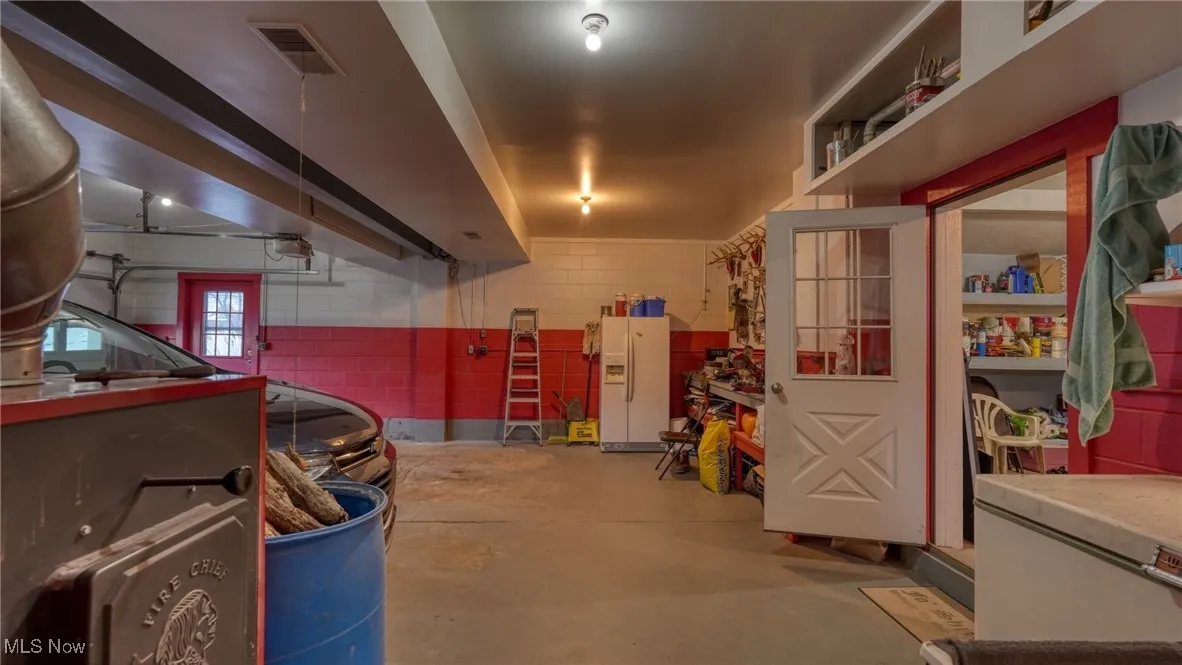 Garage with a garage door opener and white fridge with ice dispenser