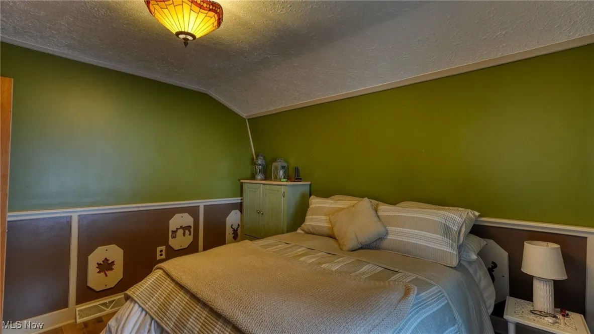 Bedroom featuring lofted ceiling and a textured ceiling