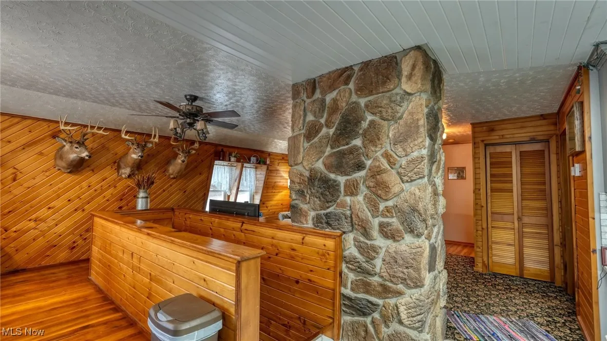 View of living area with wood flooring, wooden walls, and a textured ceiling