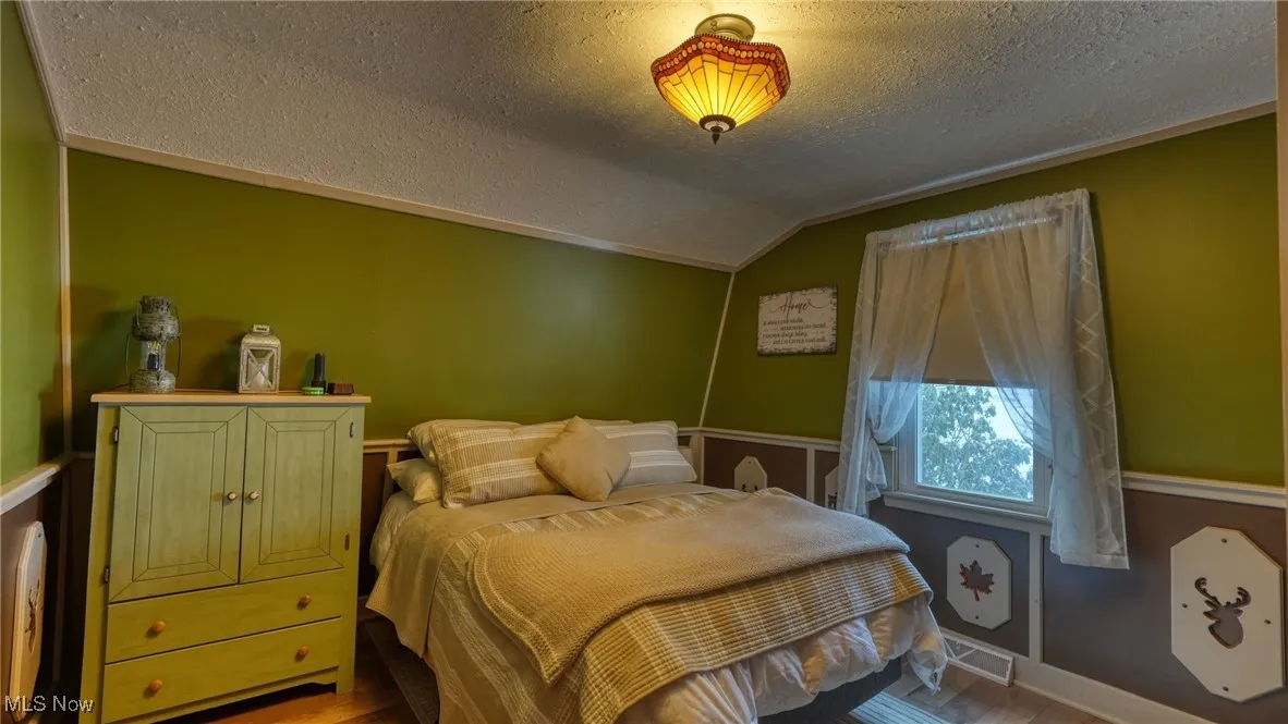 Bedroom with vaulted ceiling and a textured ceiling