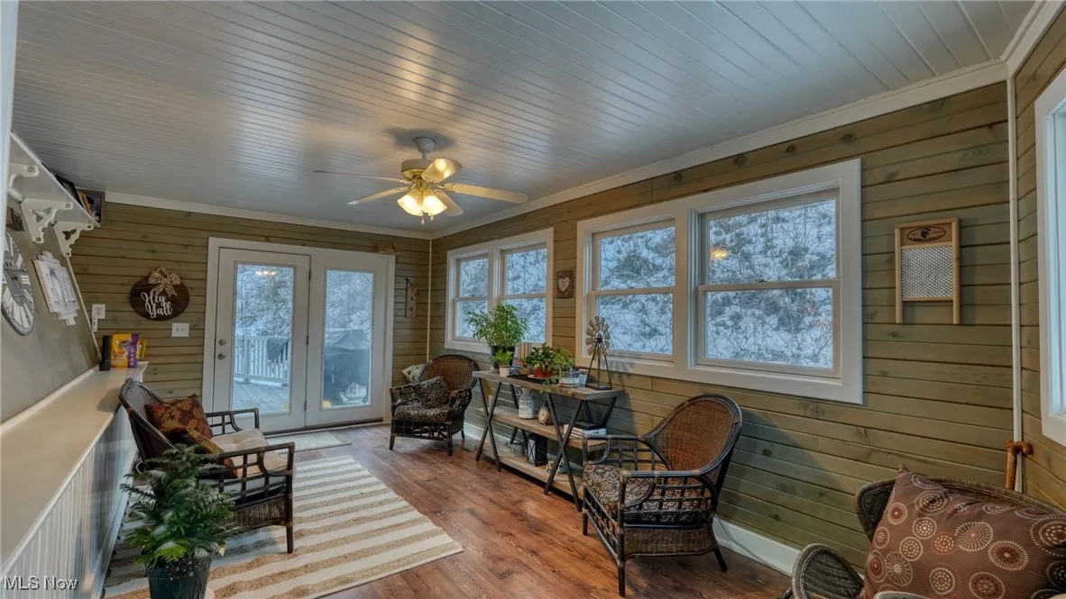 Sunroom / solarium with a healthy amount of sunlight, wood ceiling, and ceiling fan