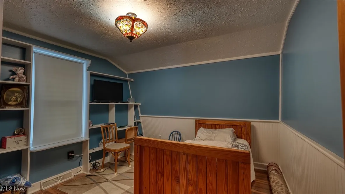 Bedroom featuring vaulted ceiling and a textured ceiling