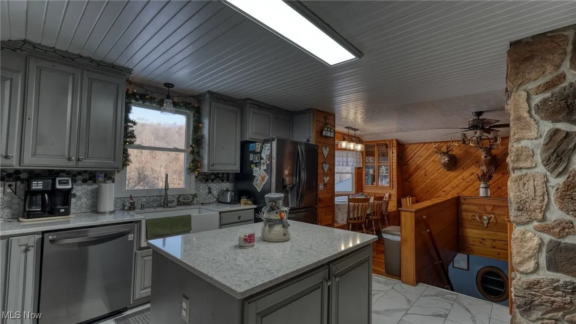Kitchen featuring a center island, dishwasher, stainless steel fridge with ice dispenser, and gray cabinetry
