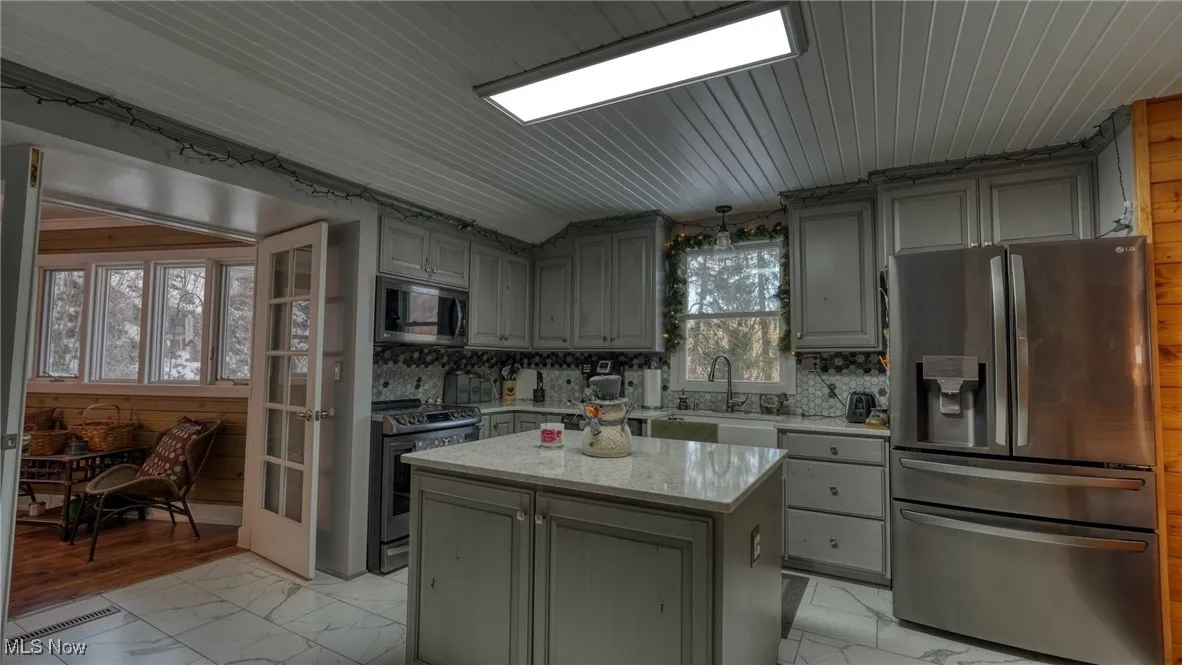 Kitchen with stainless steel appliances, a center island, sink, and decorative backsplash
