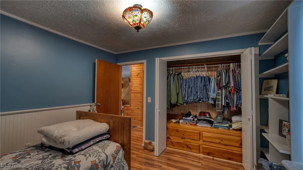 Bedroom with wood-type flooring, a closet, and a textured ceiling
