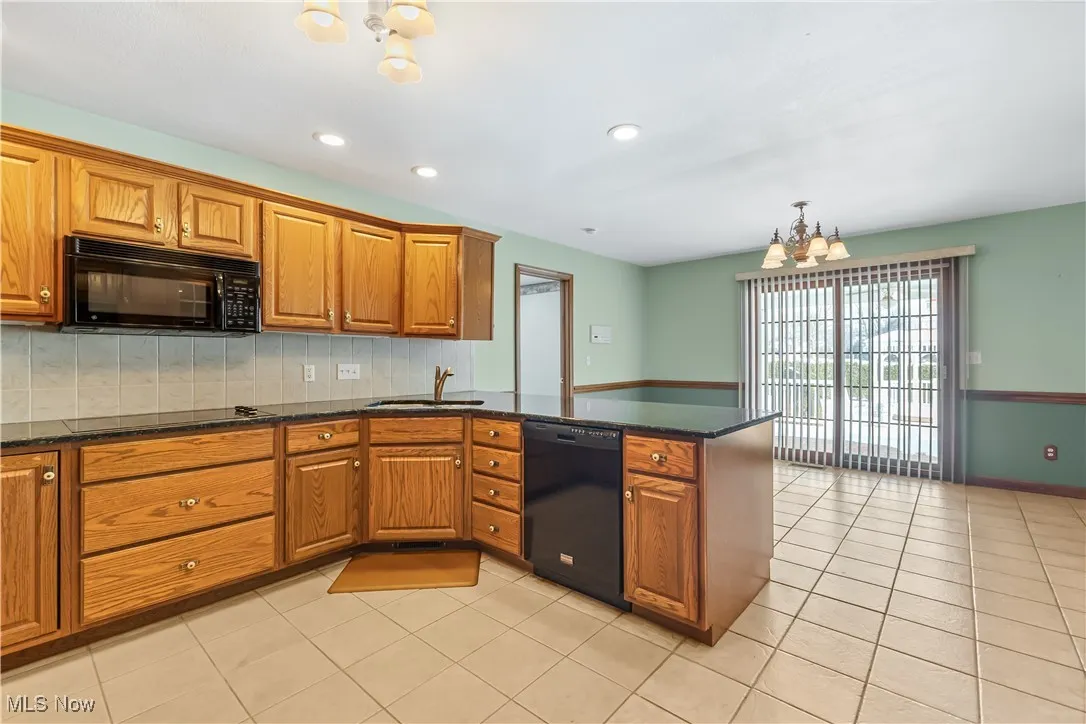 Kitchen featuring pendant lighting, black appliances, sink, a chandelier, and kitchen​​‌​​​​‌​​‌‌​‌‌​​​‌‌​‌​‌​‌​​​‌​​ peninsula