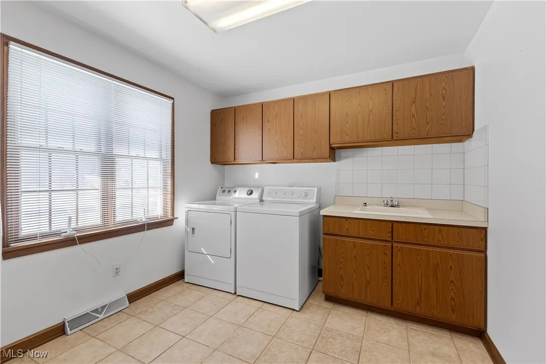 Washroom featuring washer and dryer, sink, light tile patterned floors, and cabinets