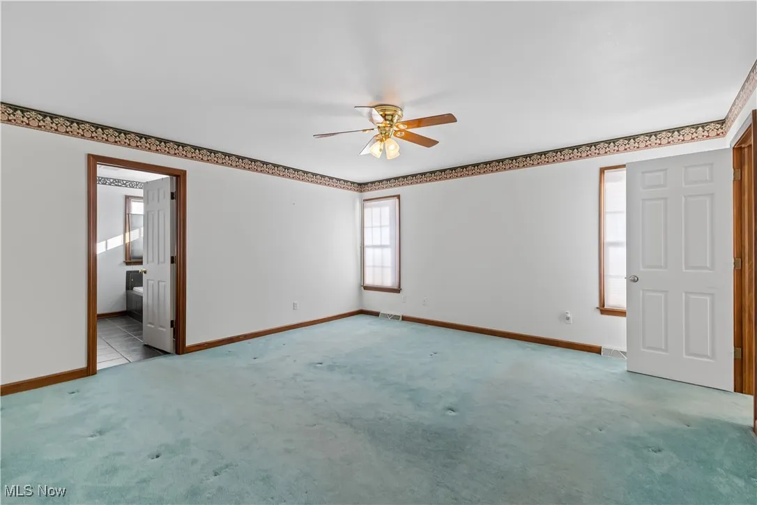 Carpeted empty room featuring ceiling fan