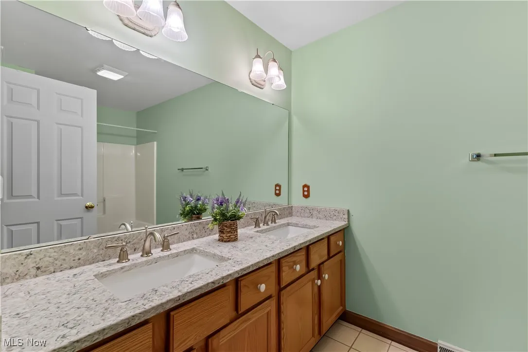 Bathroom with walk in shower, vanity, and tile patterned flooring