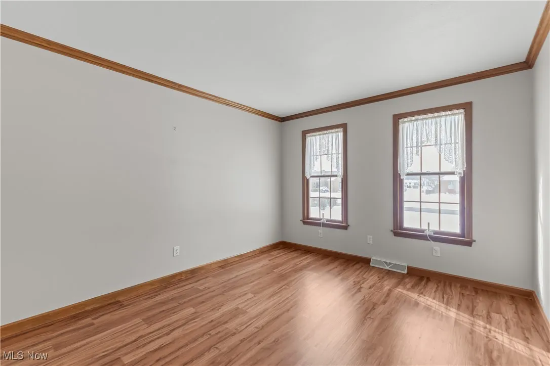 Empty room with crown molding and light hardwood / wood-style floors