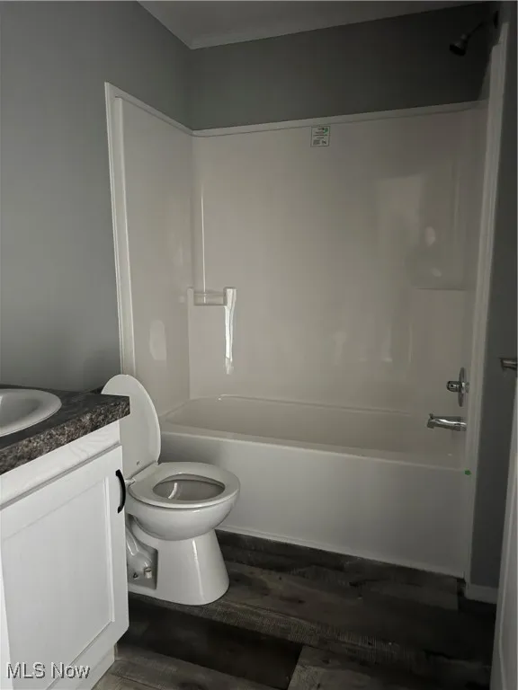 Full bathroom with hardwood / wood-style flooring, vanity, bathing tub / shower combination, and toilet
