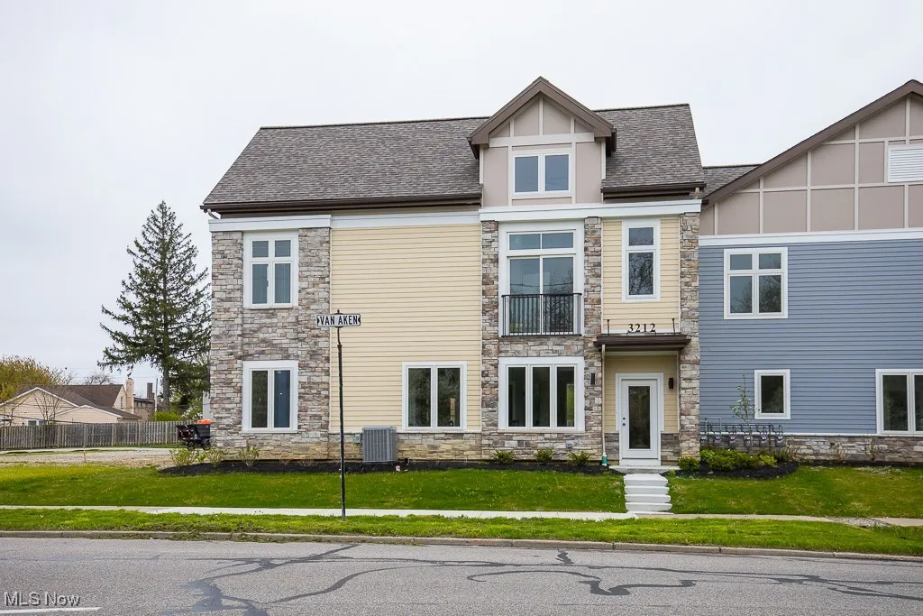 View of front facade featuring central AC, a balcony, and a front lawn