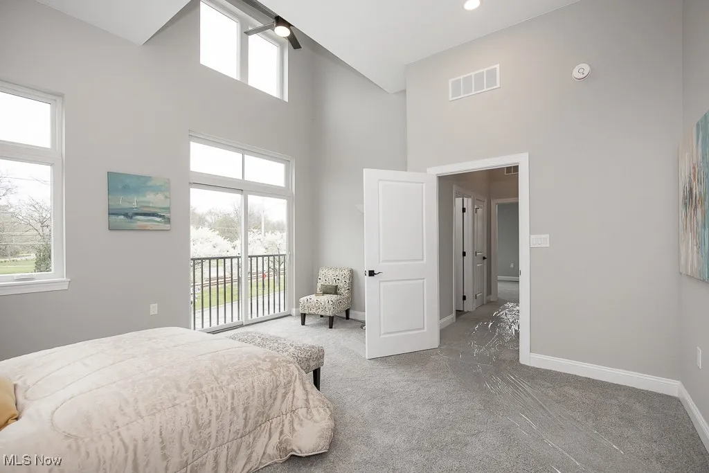 Carpeted bedroom with ceiling fan, a towering ceiling, and access to exterior