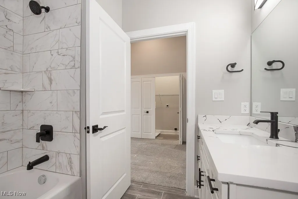 Bathroom featuring tiled shower / bath combo and vanity