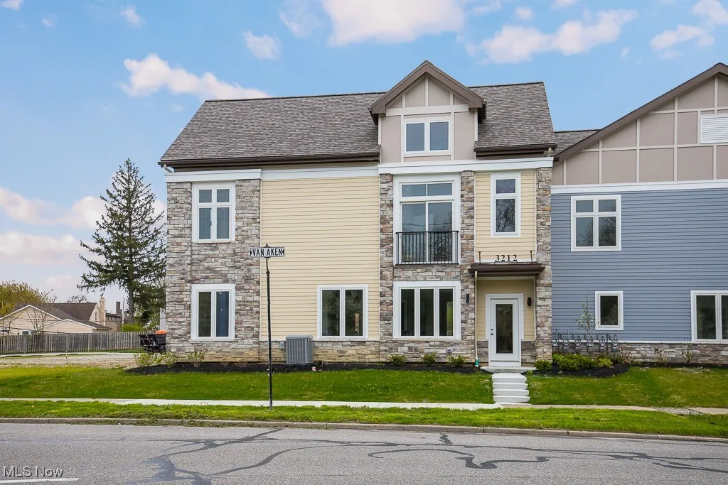 View of front facade featuring central AC, a balcony, and a front lawn