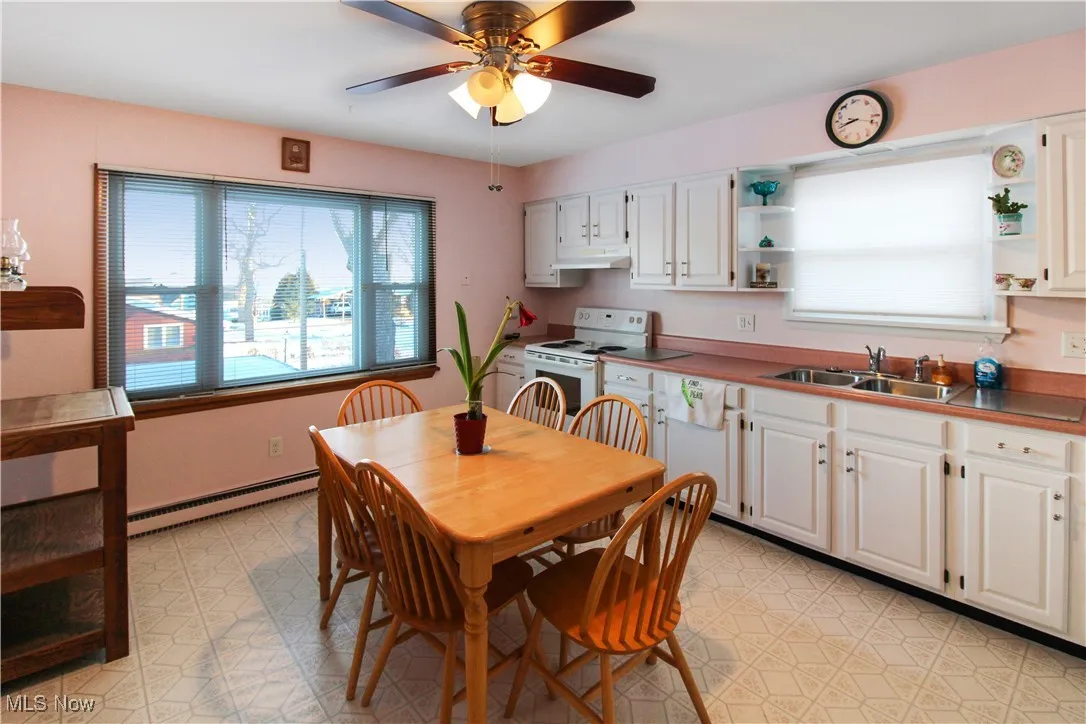Dining area with ceiling fan, sink, and a baseboard heating unit
