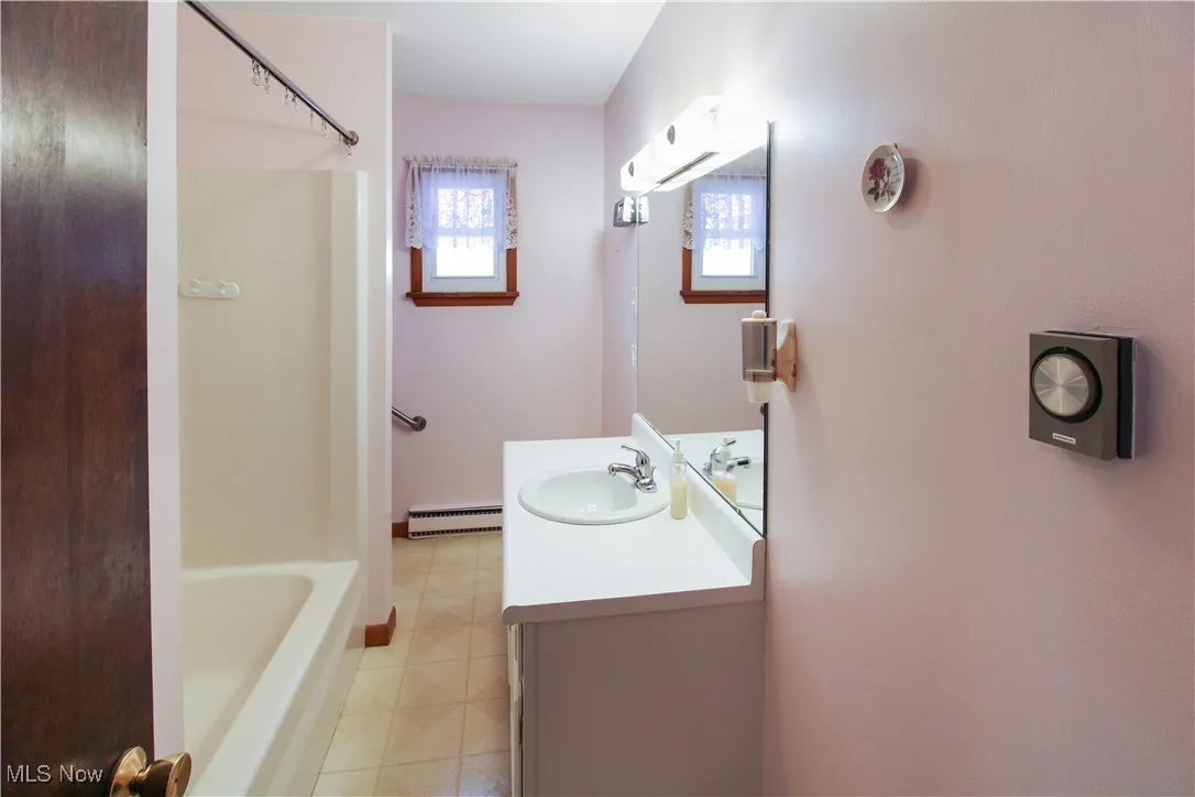 Bathroom with tile patterned flooring, vanity, and baseboard heating