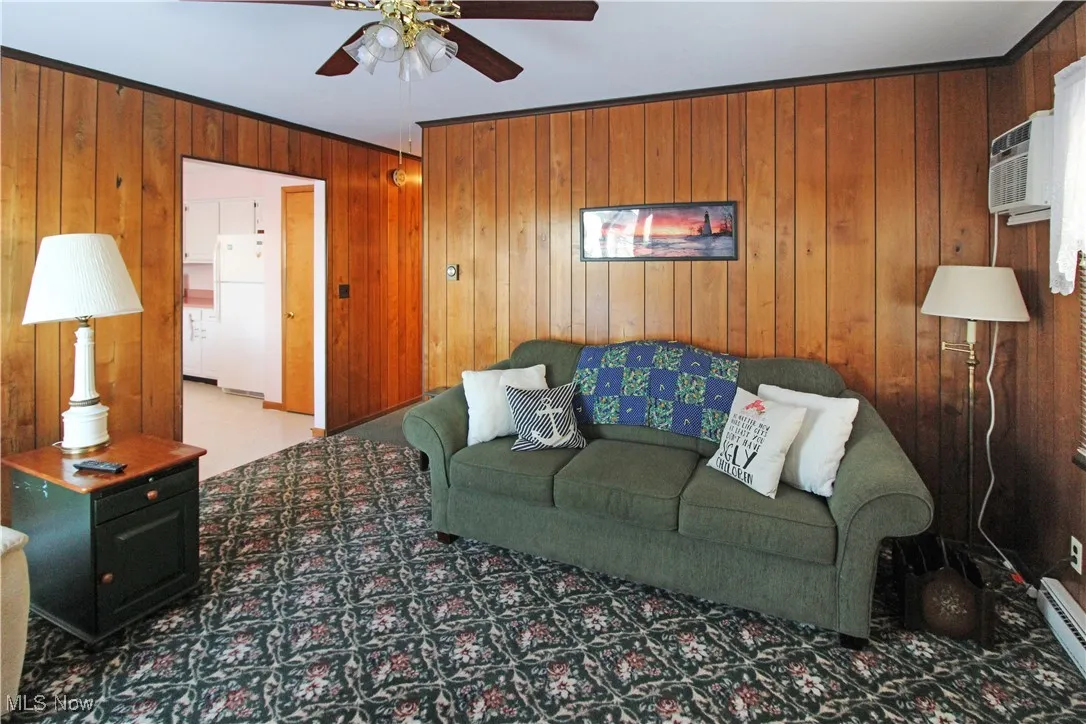 Living room featuring ceiling fan, carpet flooring, a wall mounted AC, and wooden walls