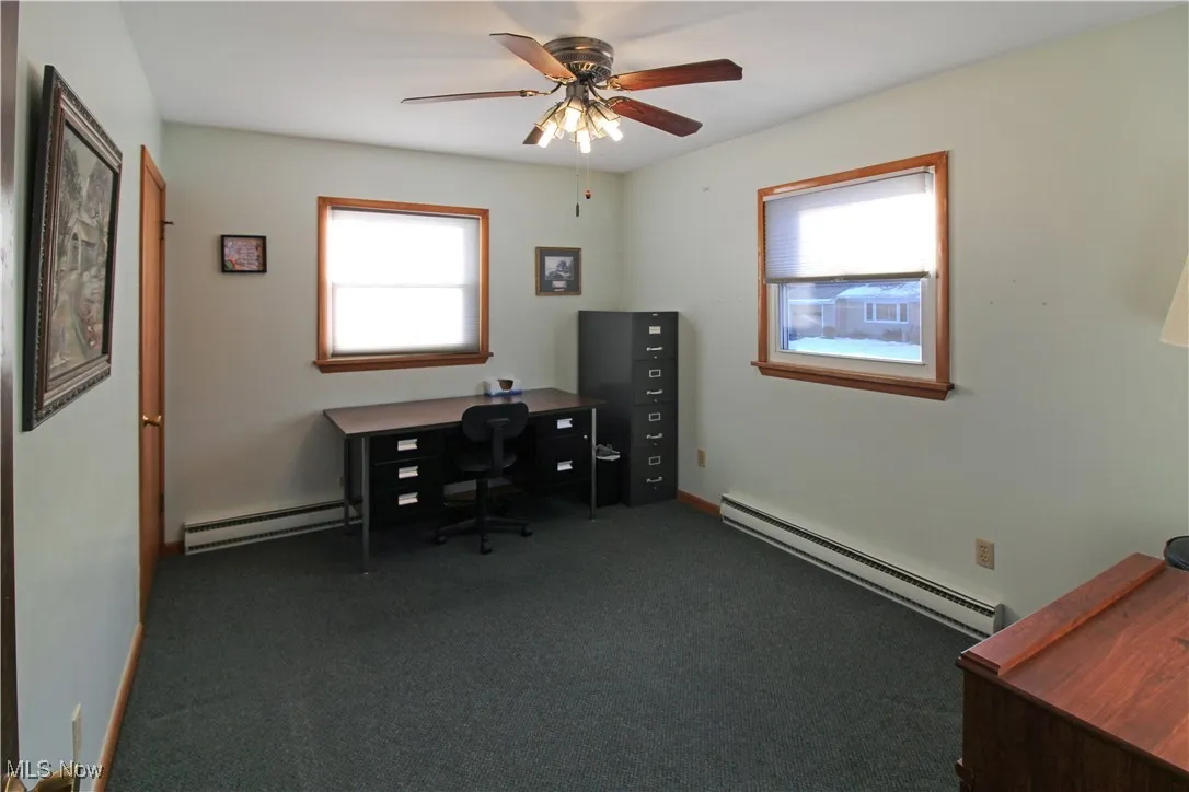 Carpeted home office with a baseboard heating unit and ceiling fan