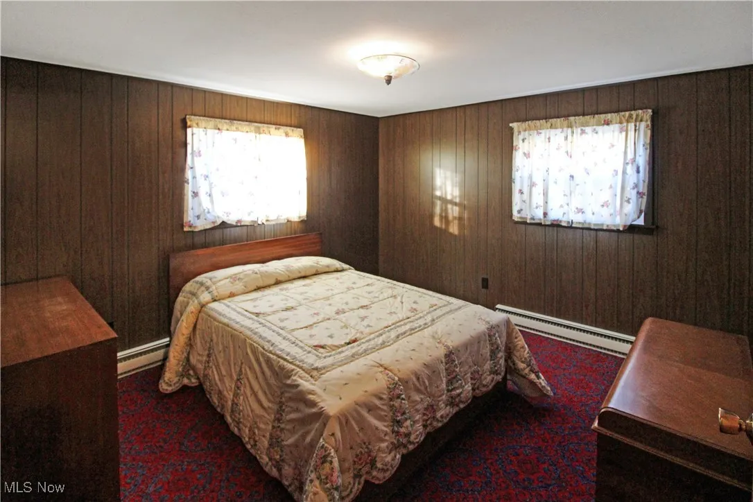 Bedroom with a baseboard radiator and wooden walls